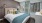 a bed with a blue and yellow comforter in a room with a window and a wood floor