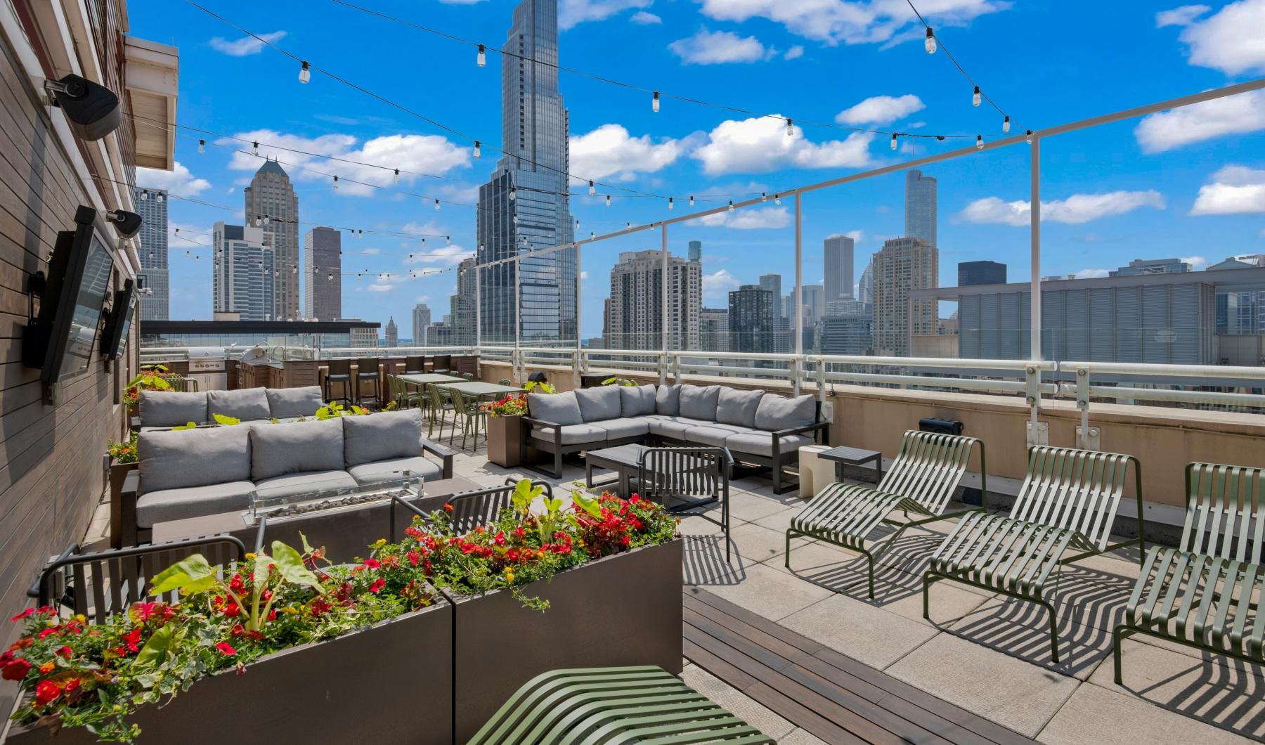 a rooftop patio with chairs and tables and a view of a city